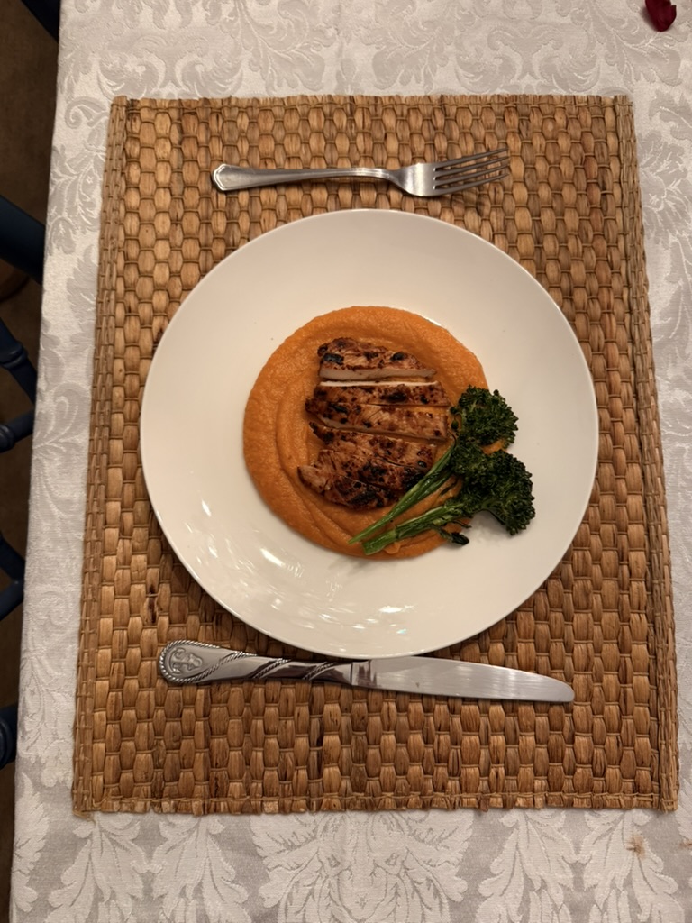 Plated chicken course with carrot purée at a private dinner party